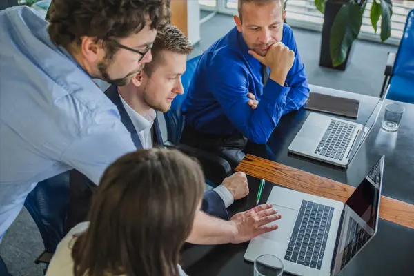 Equipo de profesionales en una oficina trabajando con un ordenador durante una sesión de formación en IA y análisis de datos.